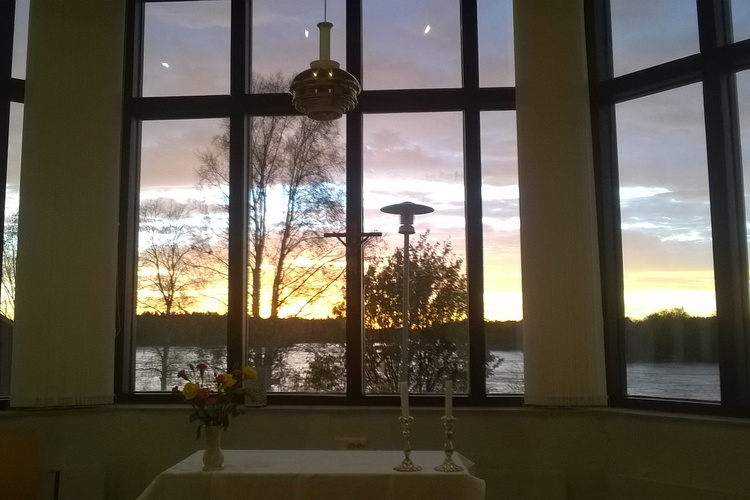 Ikkunasta näkyy Iin seurakuntatalon kappelista avautuva näkymä Iijoelle auringonlaskun aikaan.